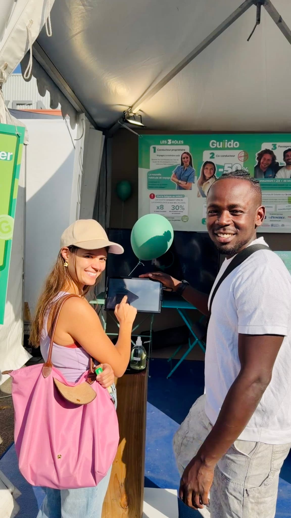 Deux visiteurs jouent au « Parcours » sur la tablette du stand Guiido